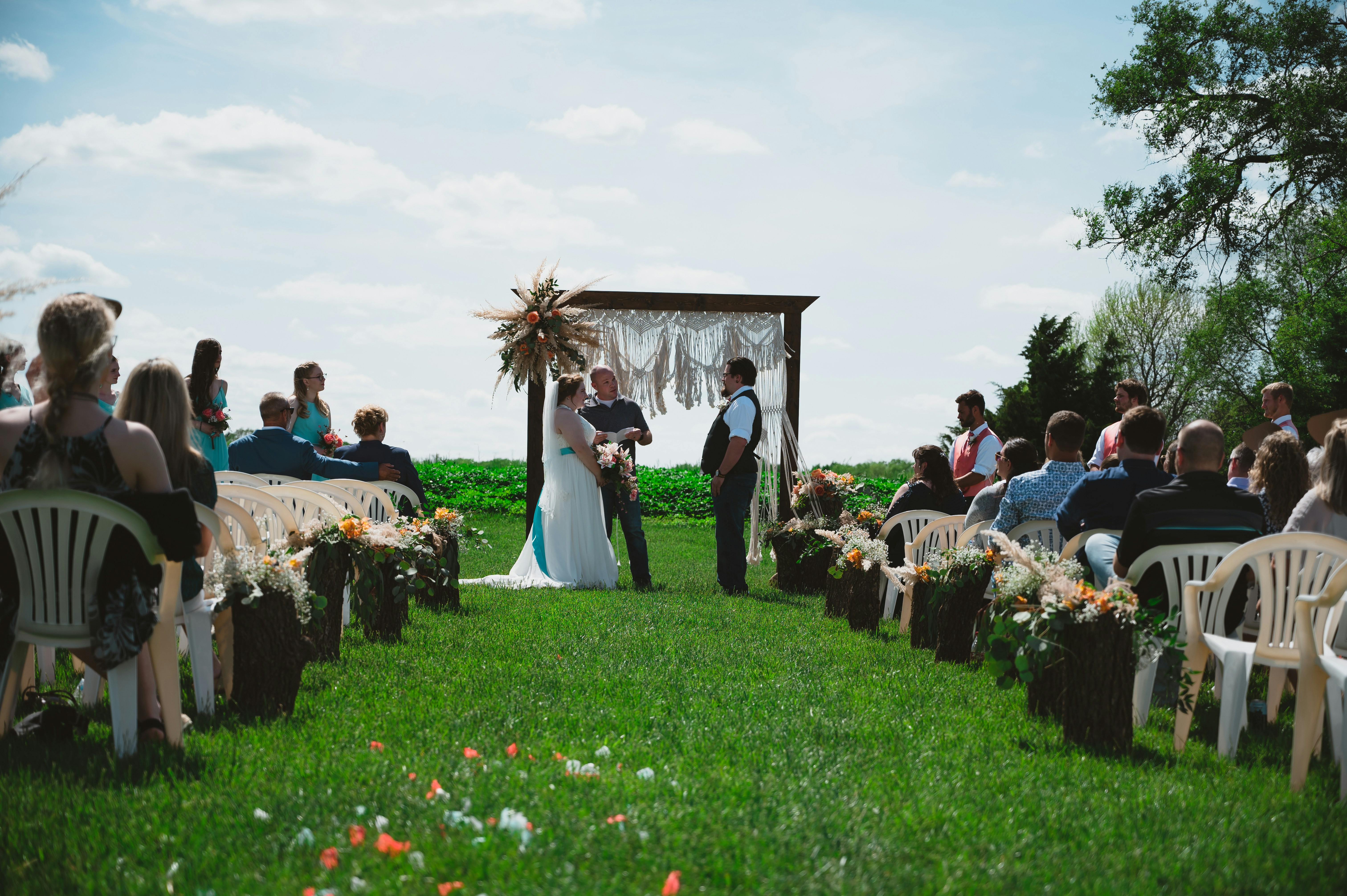 Elegant wedding ceremony outdoors, bright natural light, well-lit open garden venue, warm sunlight on couple