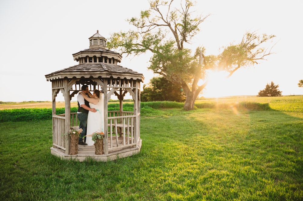 a bride and groom kissing in a wooden gazebo