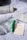 A collection of skincare products is arranged on a crumpled white fabric. Visible items include a Laneige Cream Skin toner and its box, a green skincare tube, a clear glass bottle, and a pack of Mecca Cosmetica blotting papers.