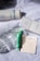 A collection of skincare products is arranged on a crumpled white fabric. Visible items include a Laneige Cream Skin toner and its box, a green skincare tube, a clear glass bottle, and a pack of Mecca Cosmetica blotting papers.