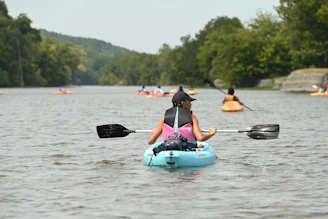 A group kayaking on a calm river with an 'Aventure' badge on the image.