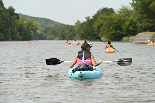 A group kayaking on a calm river with an 'Aventure' badge on the image.