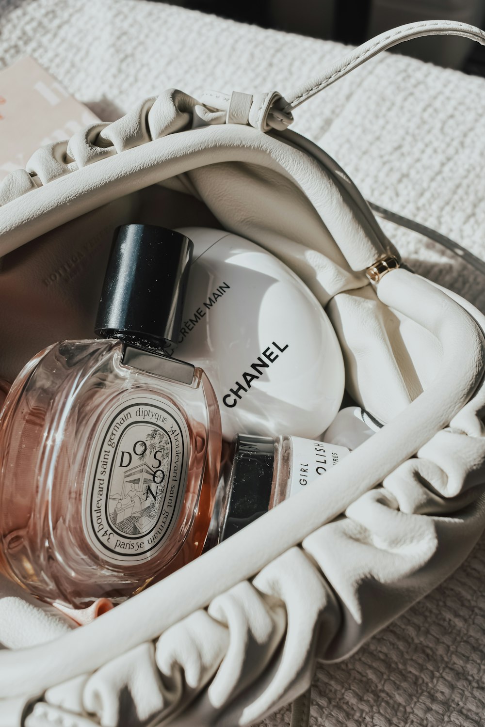 a white purse with a bottle of perfume in it
