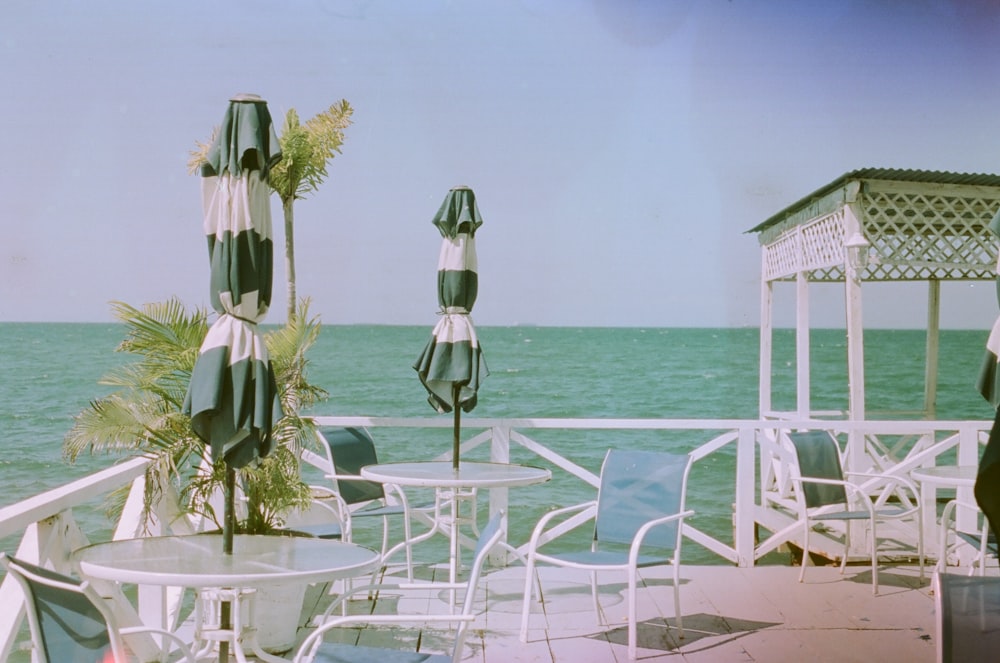 a view of the ocean from a deck with chairs and umbrellas