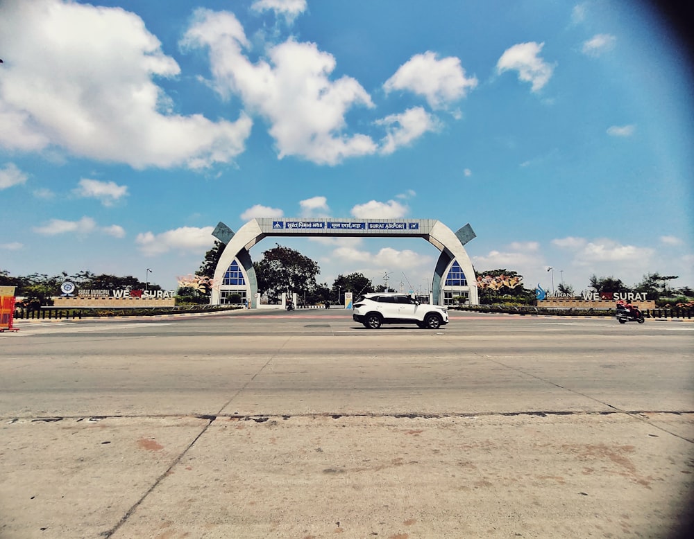 a white car is parked in front of a large arch