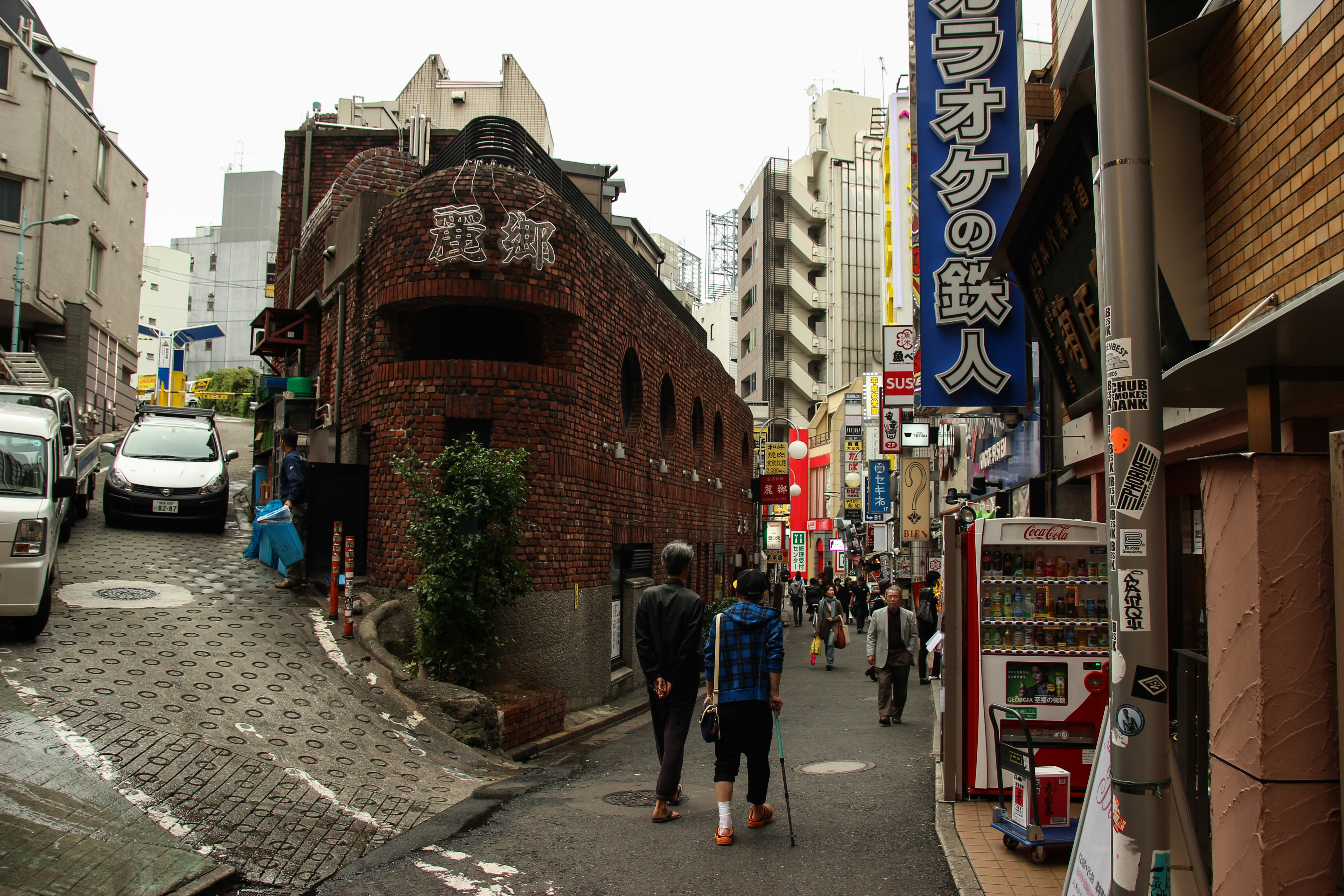 a group of people walking down a street next to tall buildings