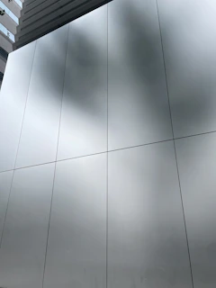Close-up of a sleek aluminum façade panel reflecting sunlight on a modern commercial building