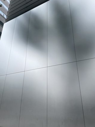 Modern building facade with glass and aluminum panels reflecting sunlight during daytime.