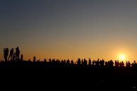 A sunset gathering with women standing together, silhouetted against a peachy pink sky.