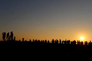 The team gathered outdoors at sunset, silhouetted against a glowing sky, symbolizing unity and purpose.