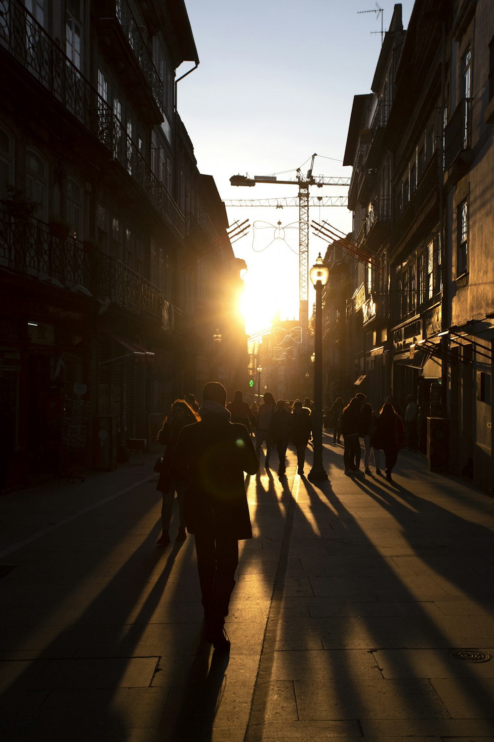 a group of people walking down a street next to tall buildings