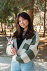 a woman standing in a park with her arms crossed
