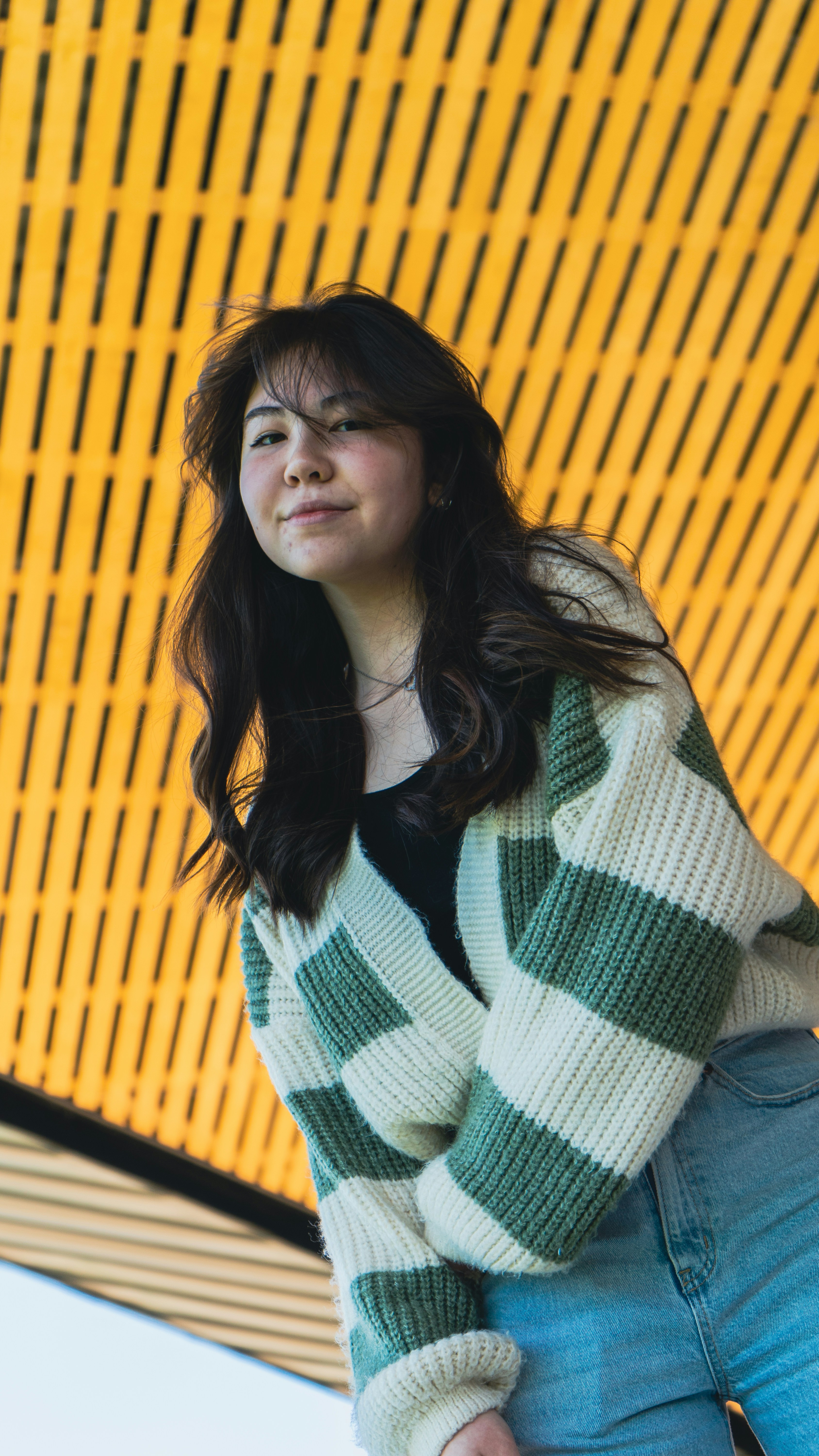 a woman standing in front of a yellow wall