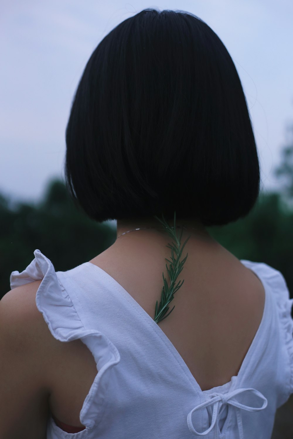 the back of a woman's neck with a plant on it