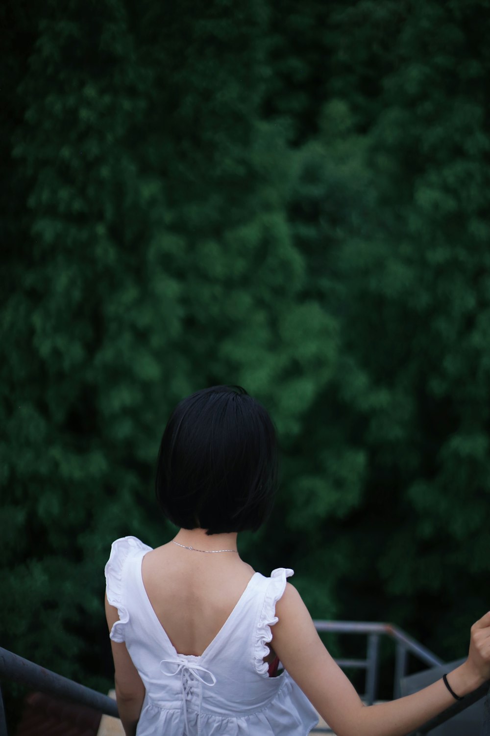 a woman in a white dress standing next to a forest