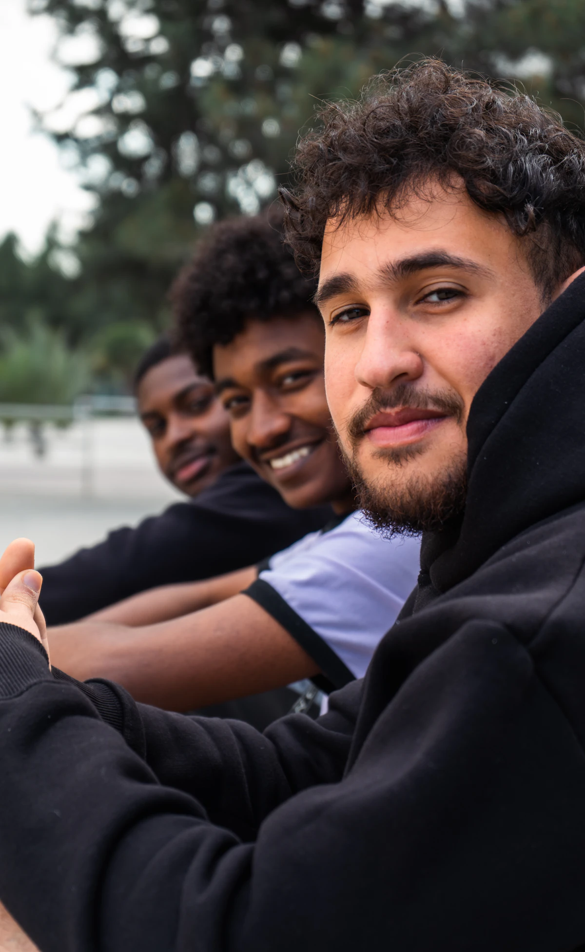Studierende in Hoodies sitzen gemeinsam auf dem Campus