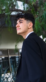 a young man in a suit standing in front of a building