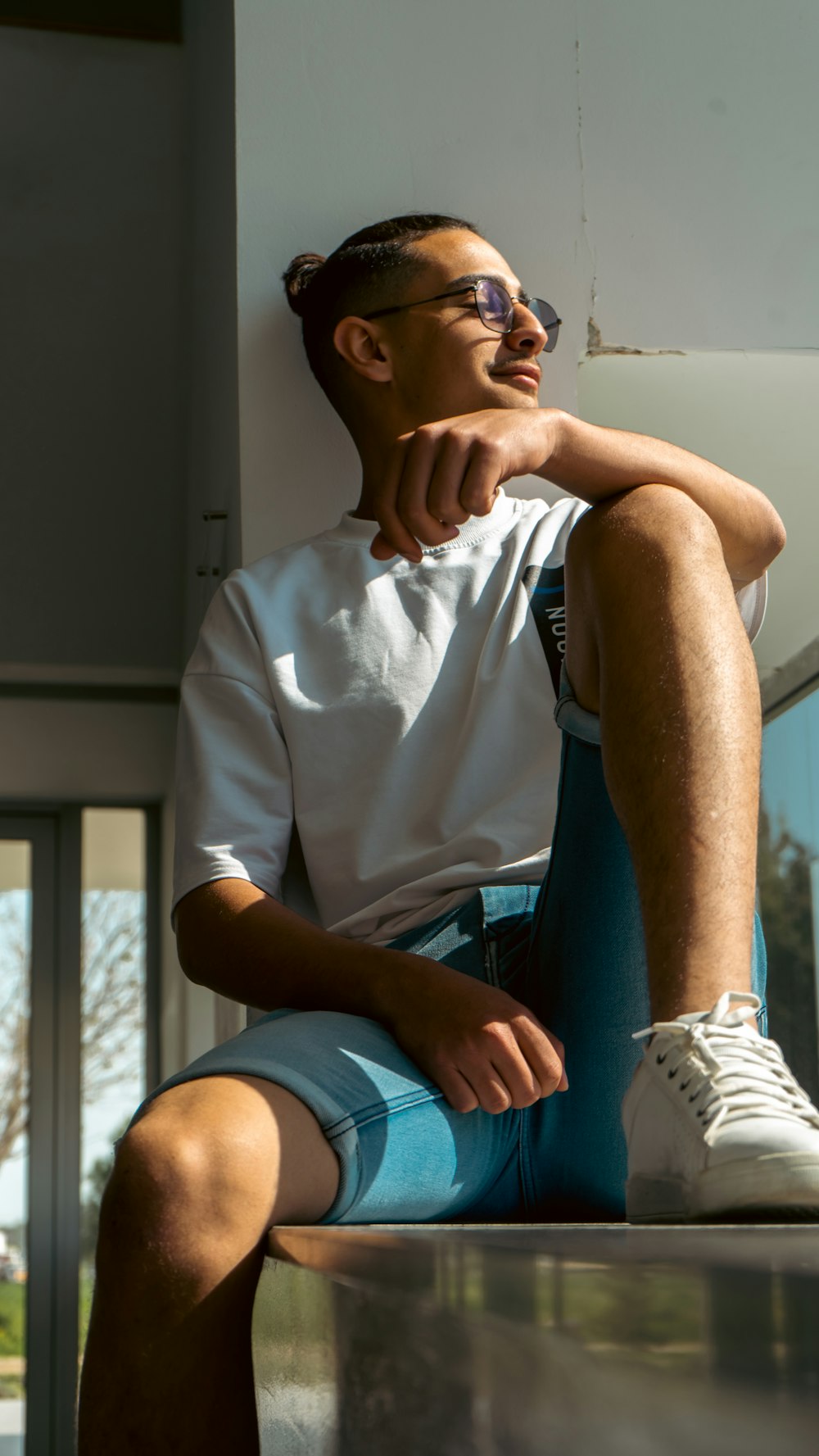a man in white shirt and blue shorts sitting on a ledge