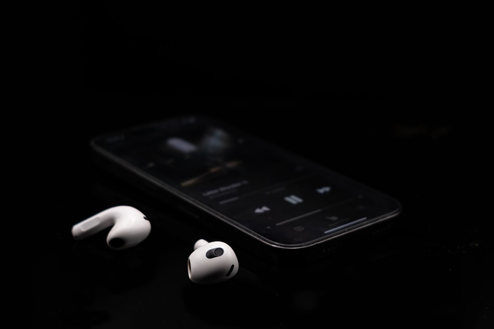 a black cell phone and earphones on a table