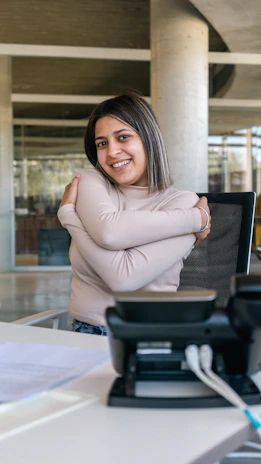 A friendly call center agent speaking on the phone with a warm smile in a modern office.