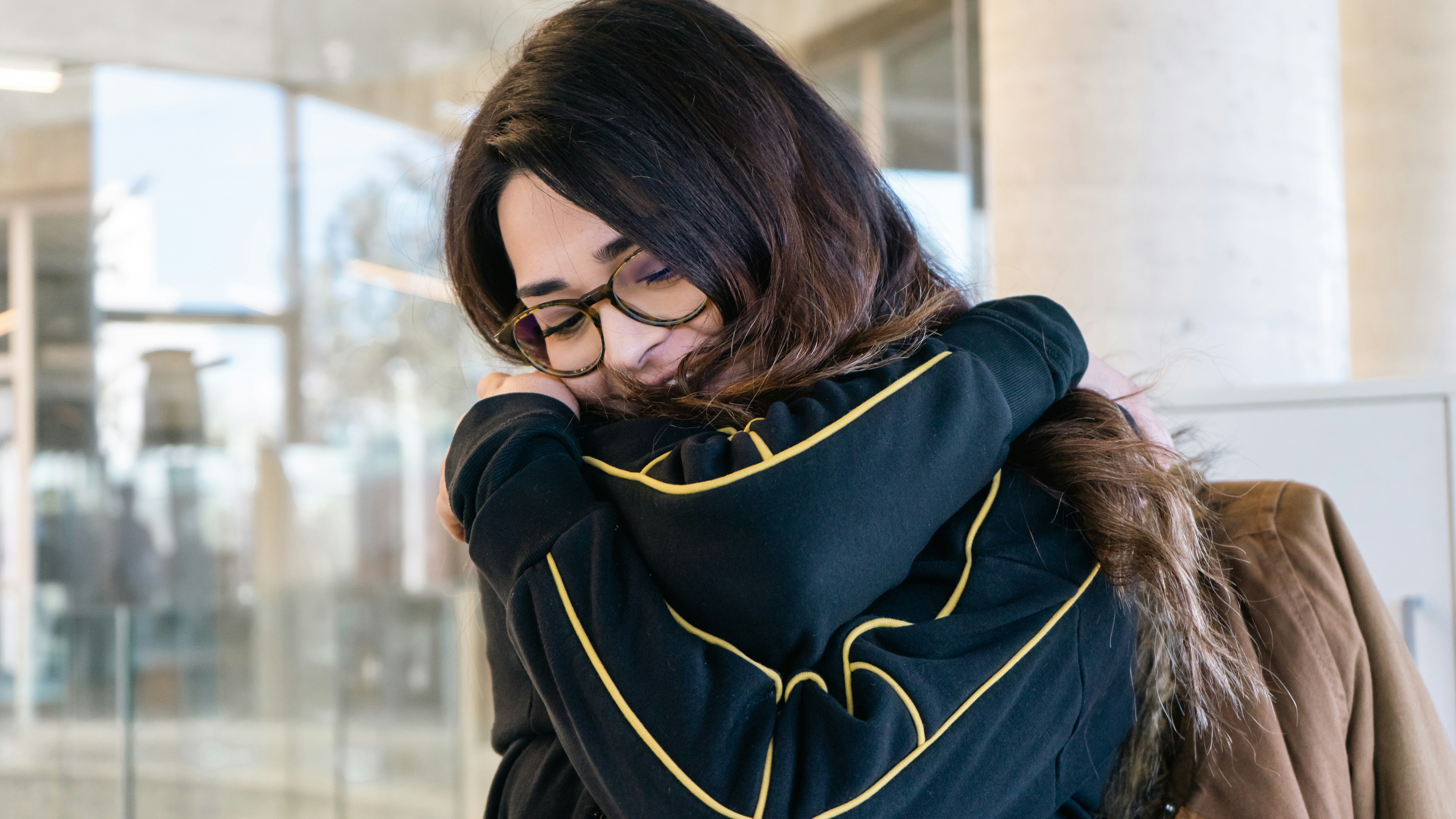 a woman with glasses is looking down at her phone