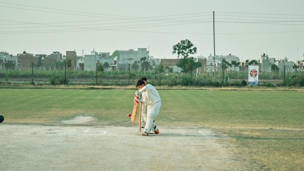 A cricket creator delivering a powerful shot on a sunny outdoor pitch, with focused intensity