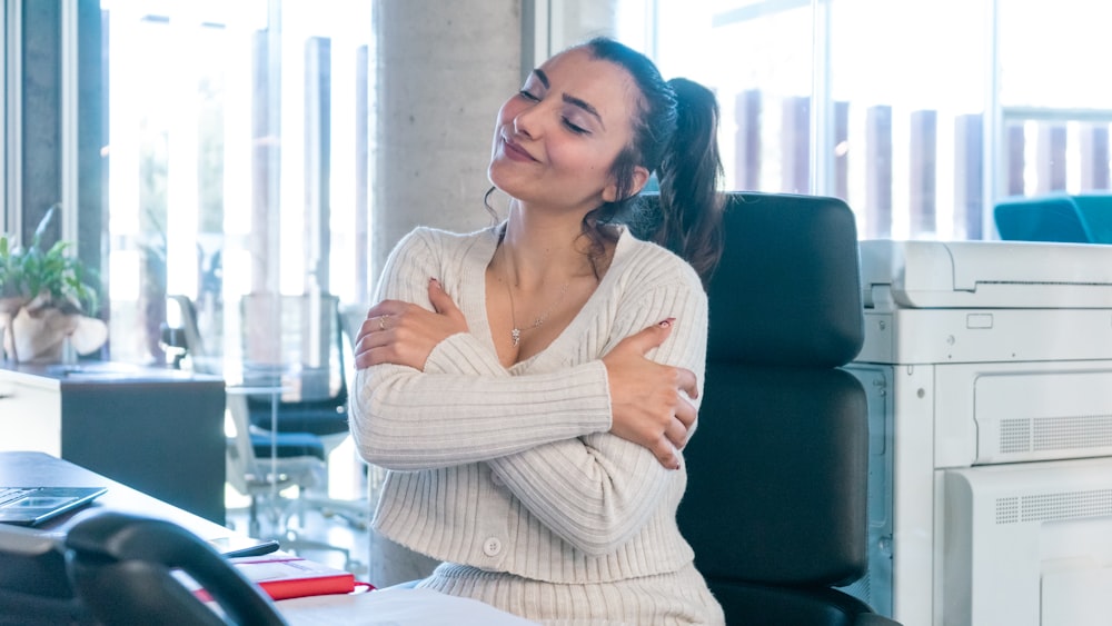 a woman sitting at a desk with her arms crossed