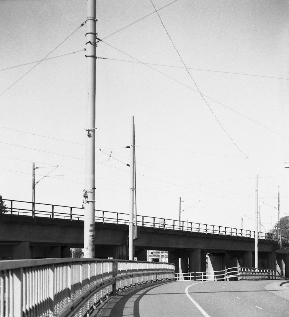 a black and white photo of a street and bridge