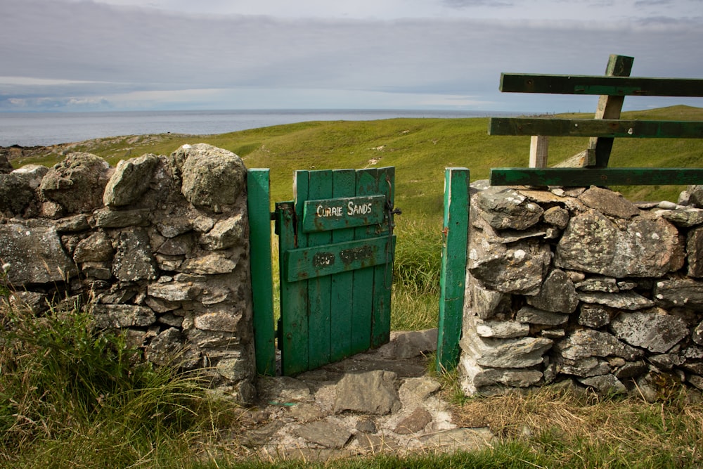 a stone wall with a green door and a wooden bench