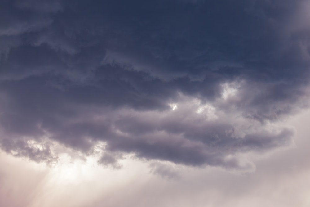 a plane flying through a cloudy sky with sunbeams