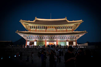 A vibrant night view of Gyeongbokgung Palace illuminated against the dark sky.
