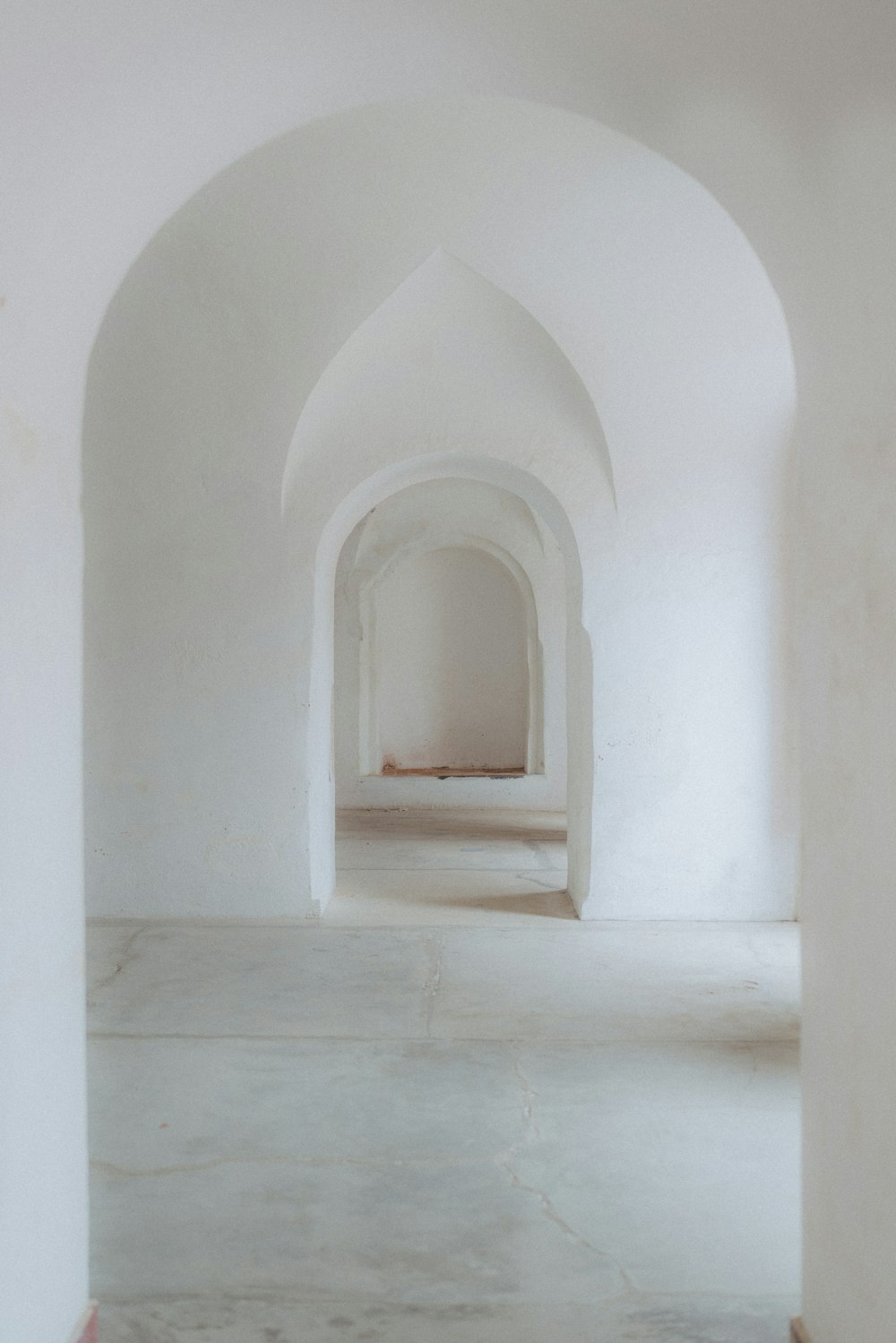 an empty room with a white wall and arches