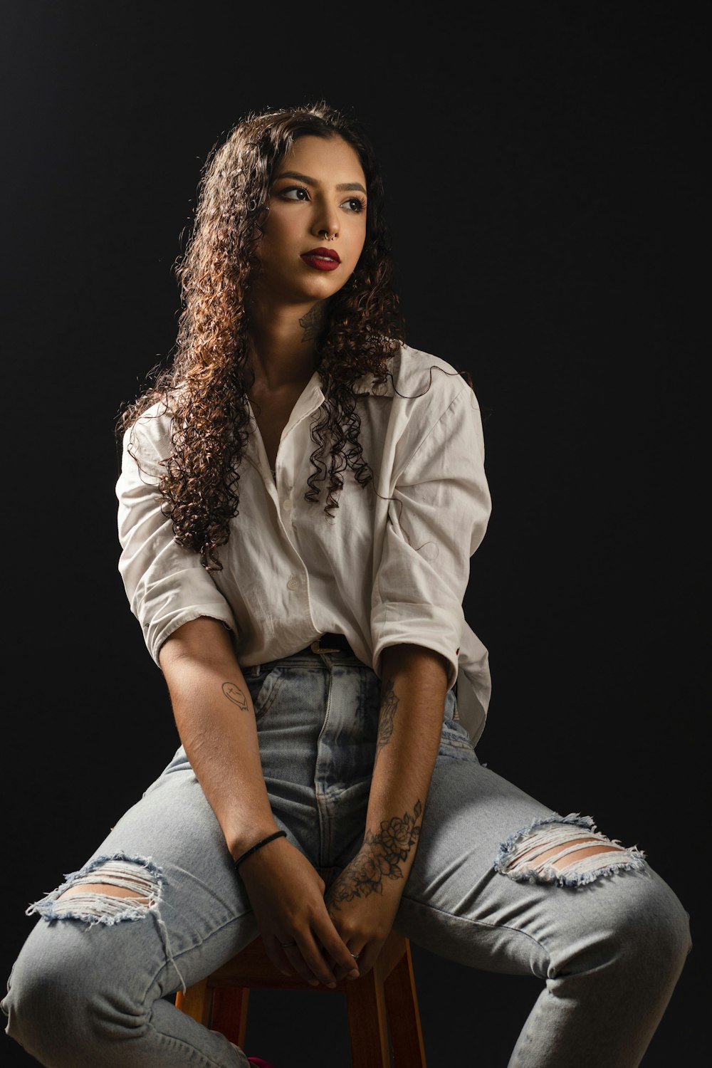 a woman sitting on top of a wooden stool