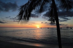 the sun is setting over the ocean with boats in the water