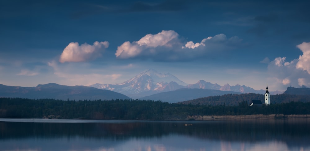 Un lago con montañas al fondo y nubes en el cielo