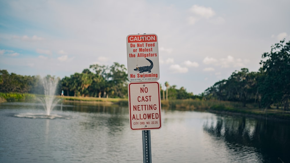 a sign on a pole in front of a body of water