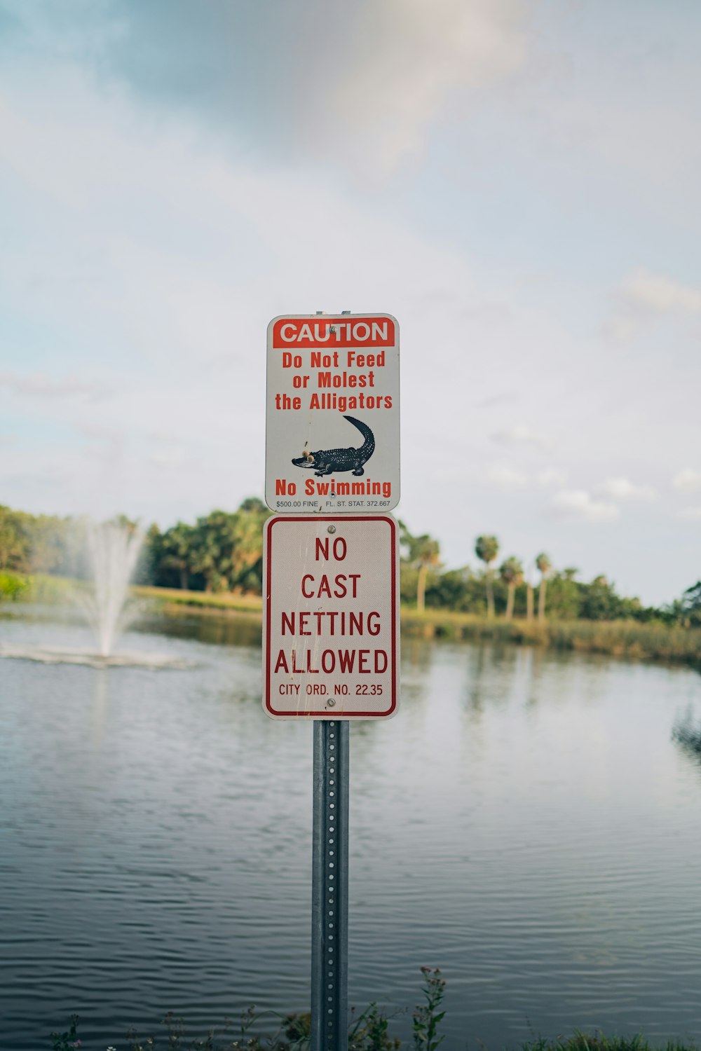 a red and white sign sitting on the side of a lake