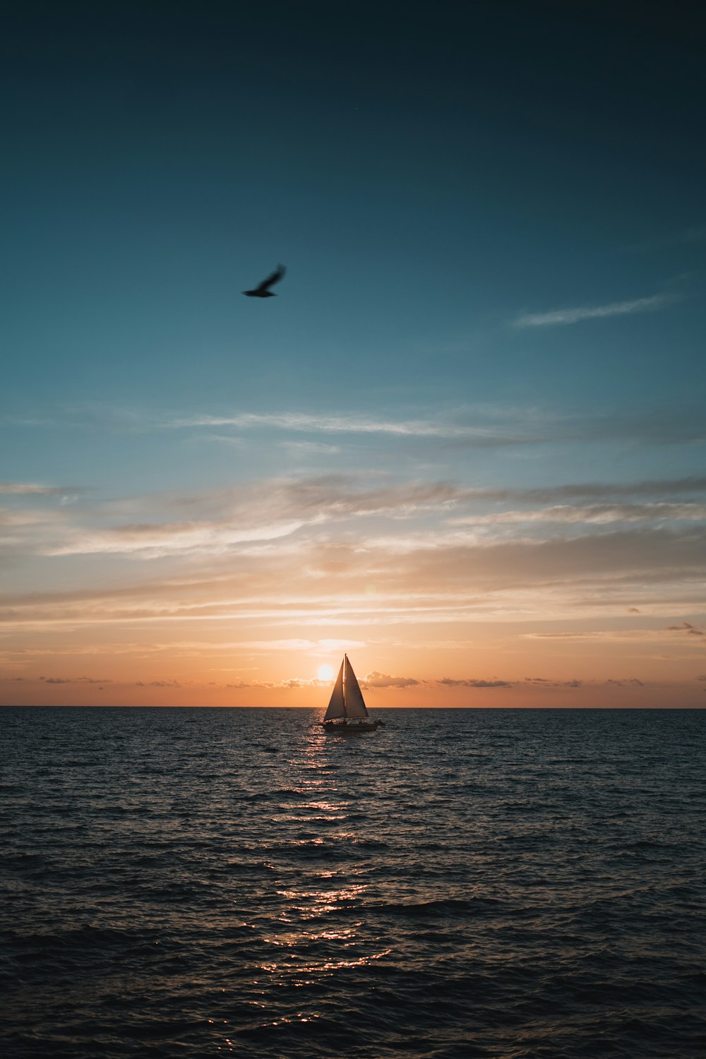 a sailboat in the ocean at sunset