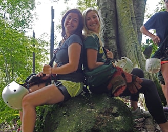 A smiling family gearing up with helmets and harnesses at the base of a sunlit rock face in the Blue Ridge Mountains.