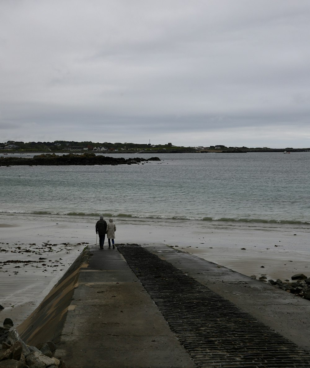 a couple of people standing on top of a pier