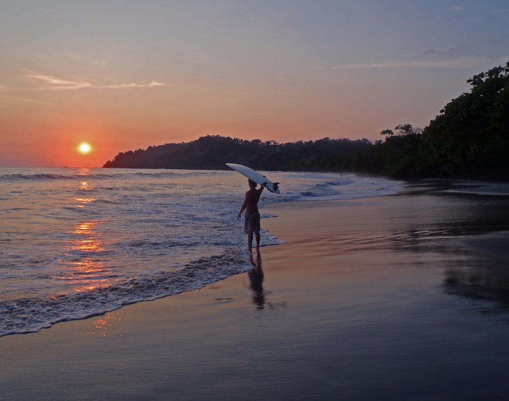 a person holding a surfboard walking on a beach