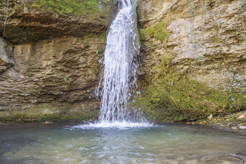 a small waterfall in the middle of a large body of water