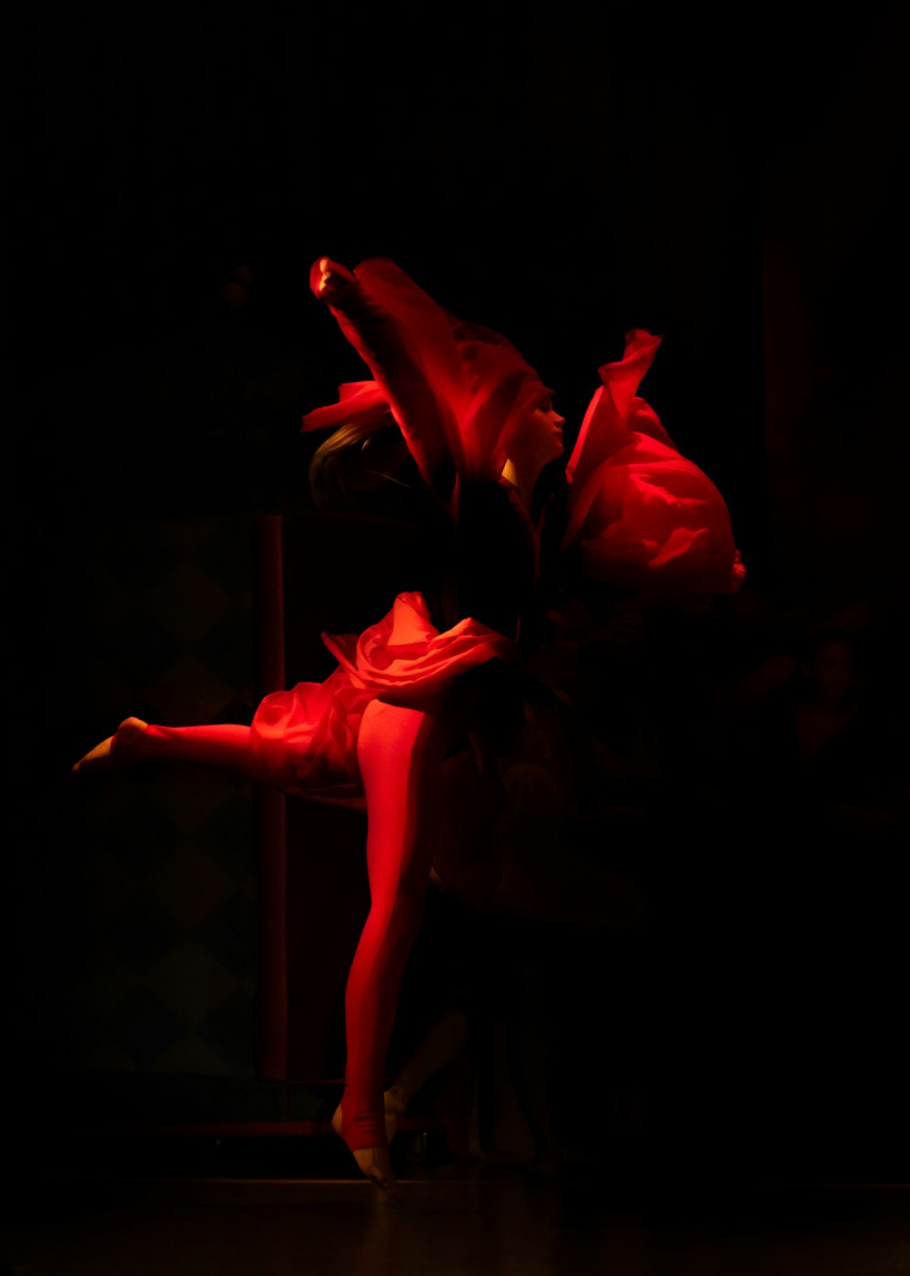 a woman in a red dress dancing in the dark