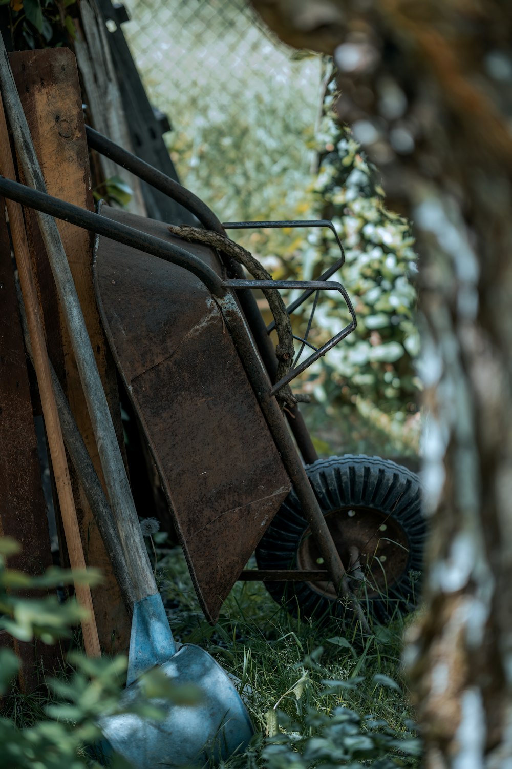 a wheelbarrow leaning against a fence in the grass