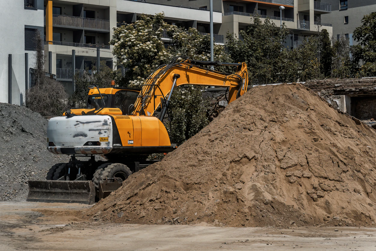 A wheeled excavator moving a pile of soil