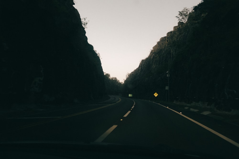 a car driving down a road next to a forest
