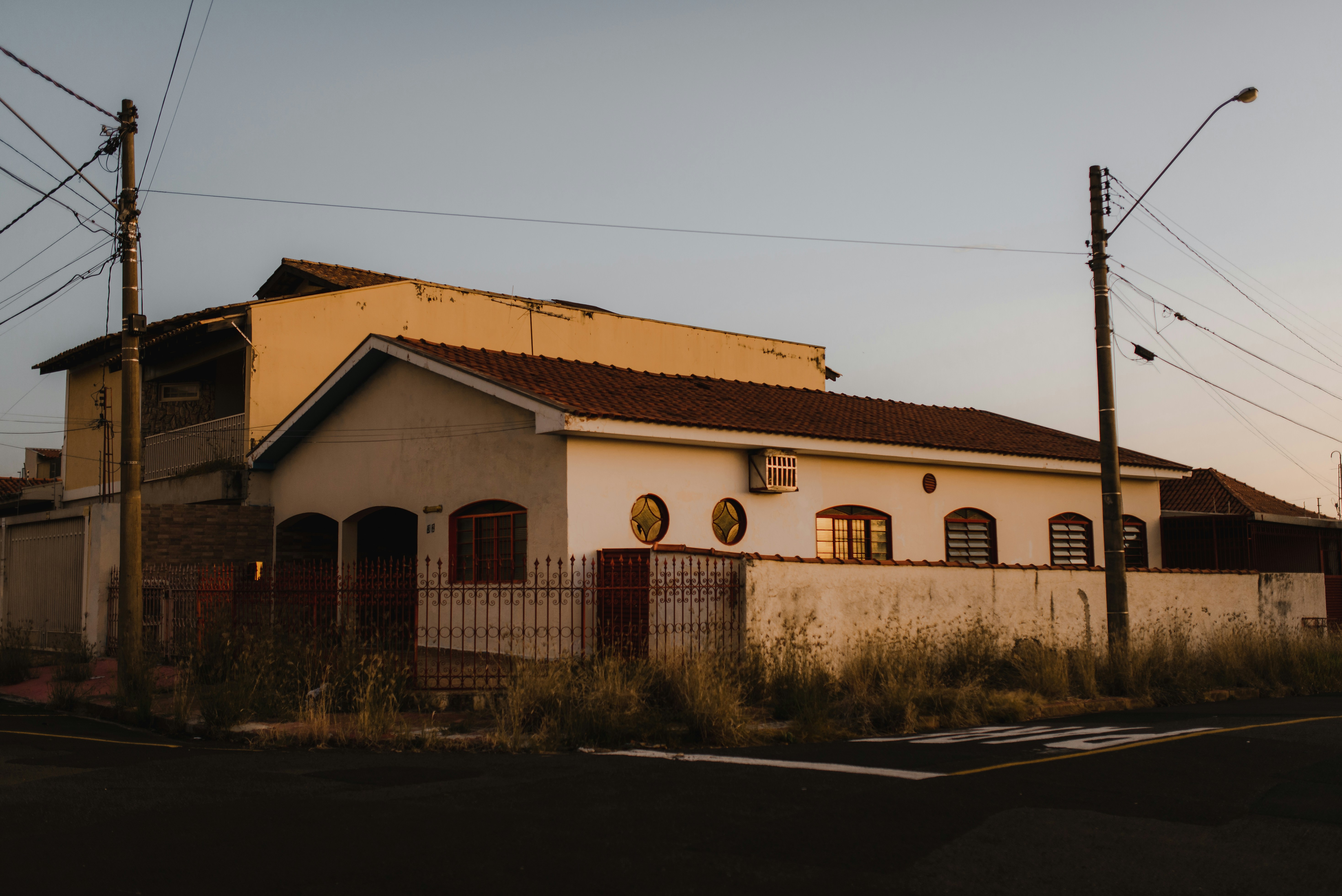 a white house with a brown roof next to a street
