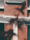 Close-up of a pressure washer removing dirt from a brick building exterior.