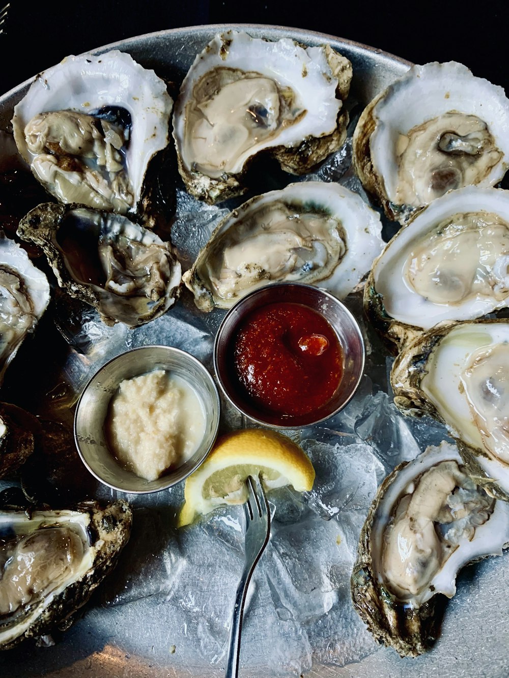 a plate of oysters with a side of ketchup