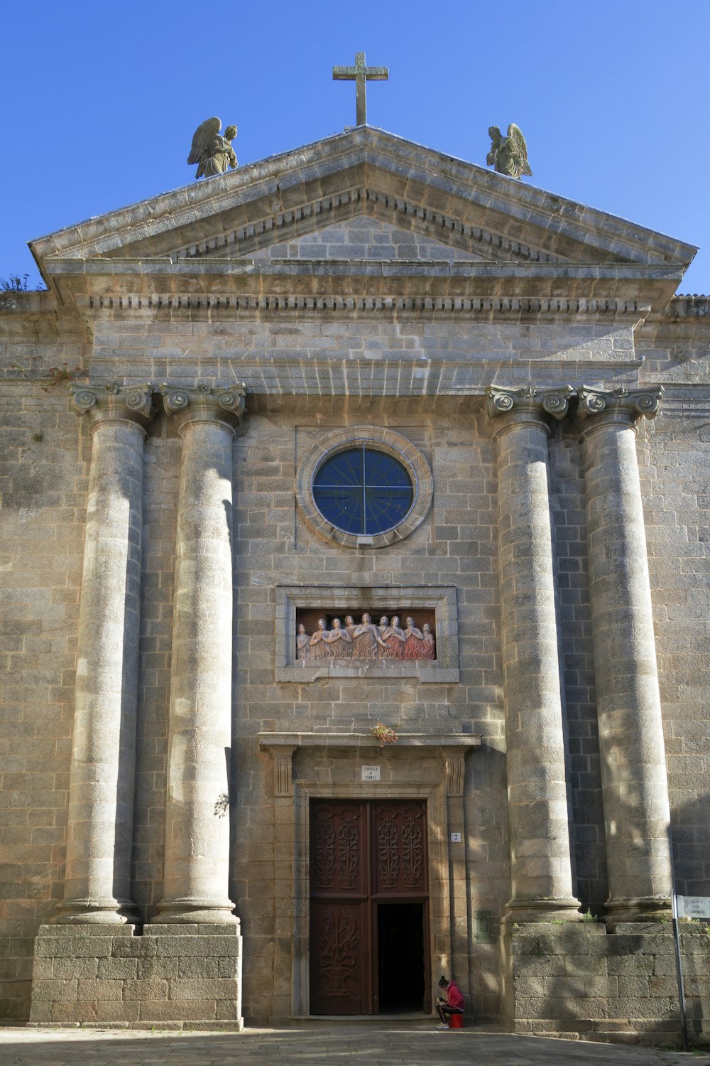 an old church with columns and a cross above it